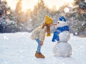 little girl outside in winter with cnowman