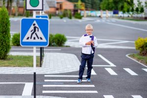 blond schoolboy with glasses backpack goes school pedestrian crosswalk