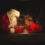 real santa claus is playing with children near christmas tree
