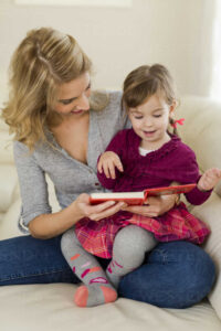 little girl sitting on her mothers lap watching a book SHKF000443
