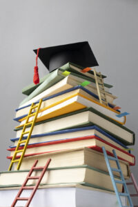 low angle stacked books graduation cap ladders education day